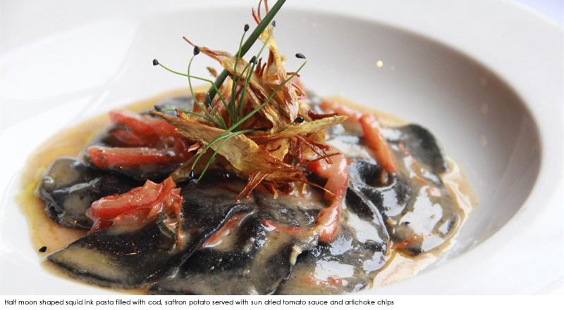 Half moon shaped squid ink pasta filled with cod, saffron potato served with sun dried tomato sauce and artichoke chips